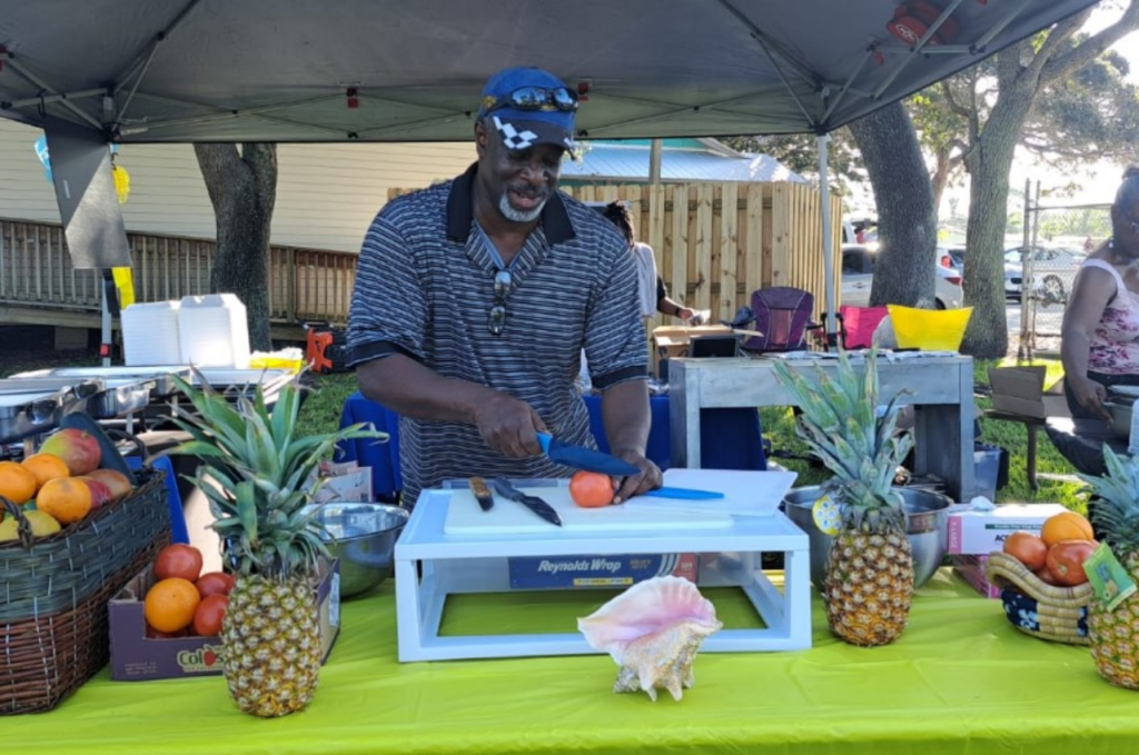 A man cutting an orange on top of a table.