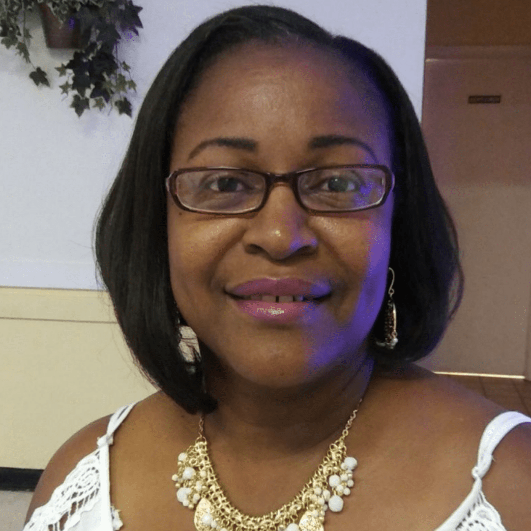 A woman with short hair wearing glasses and a necklace.